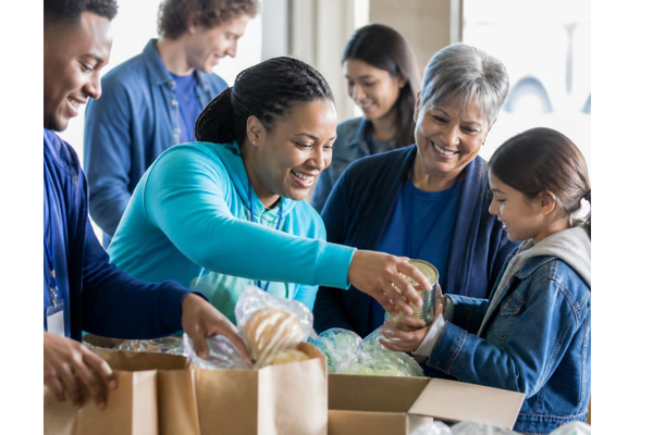 A vibrant high-quality photorealistic editorial photo of a diverse group of community members and volunteers actively engaging together in a warm, welcoming setting.